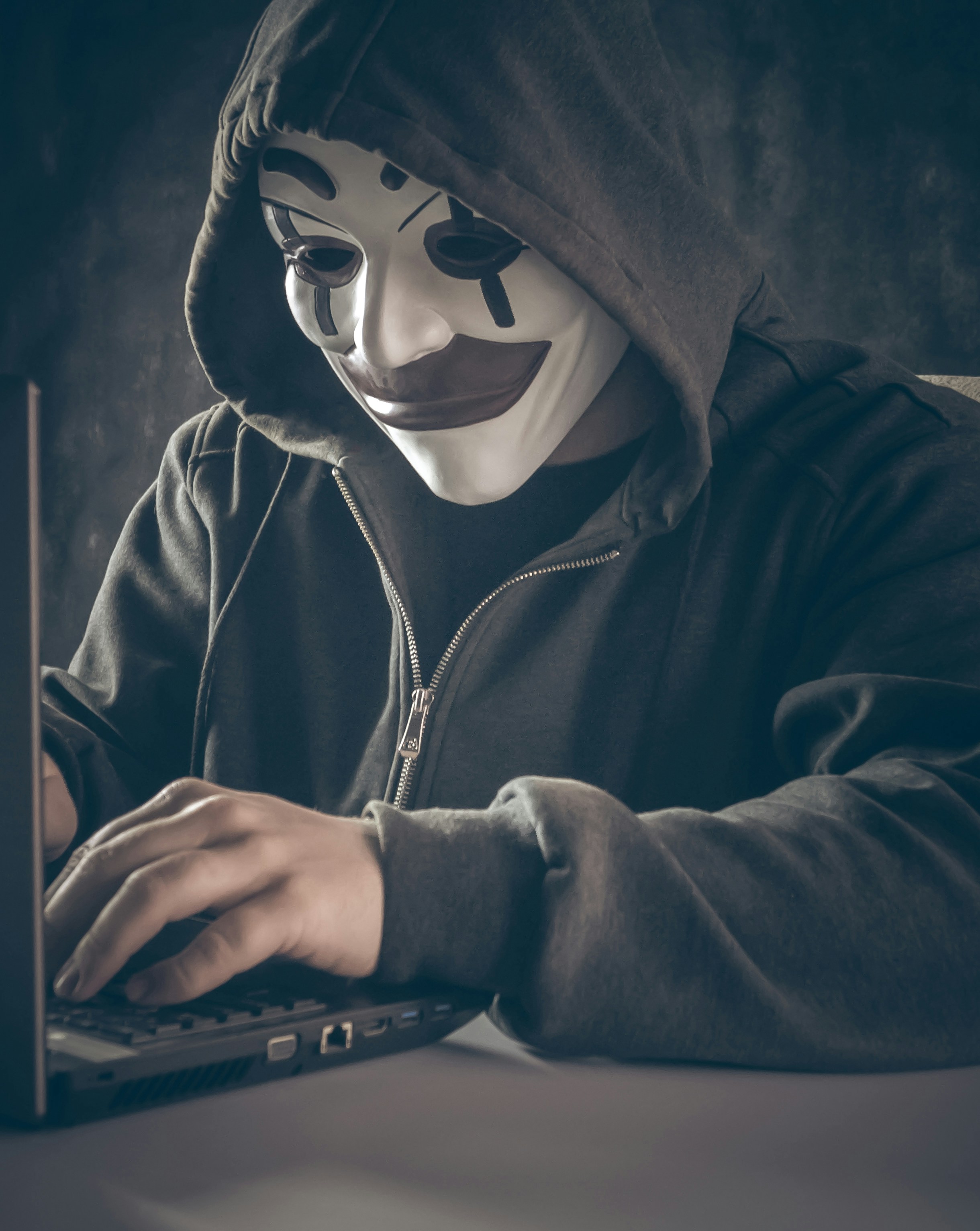 Anonymous hacker wearing a hood in a dark room
